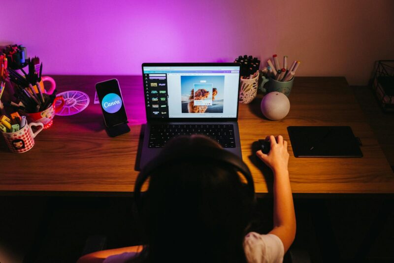 A person is using a laptop in front of a purple light